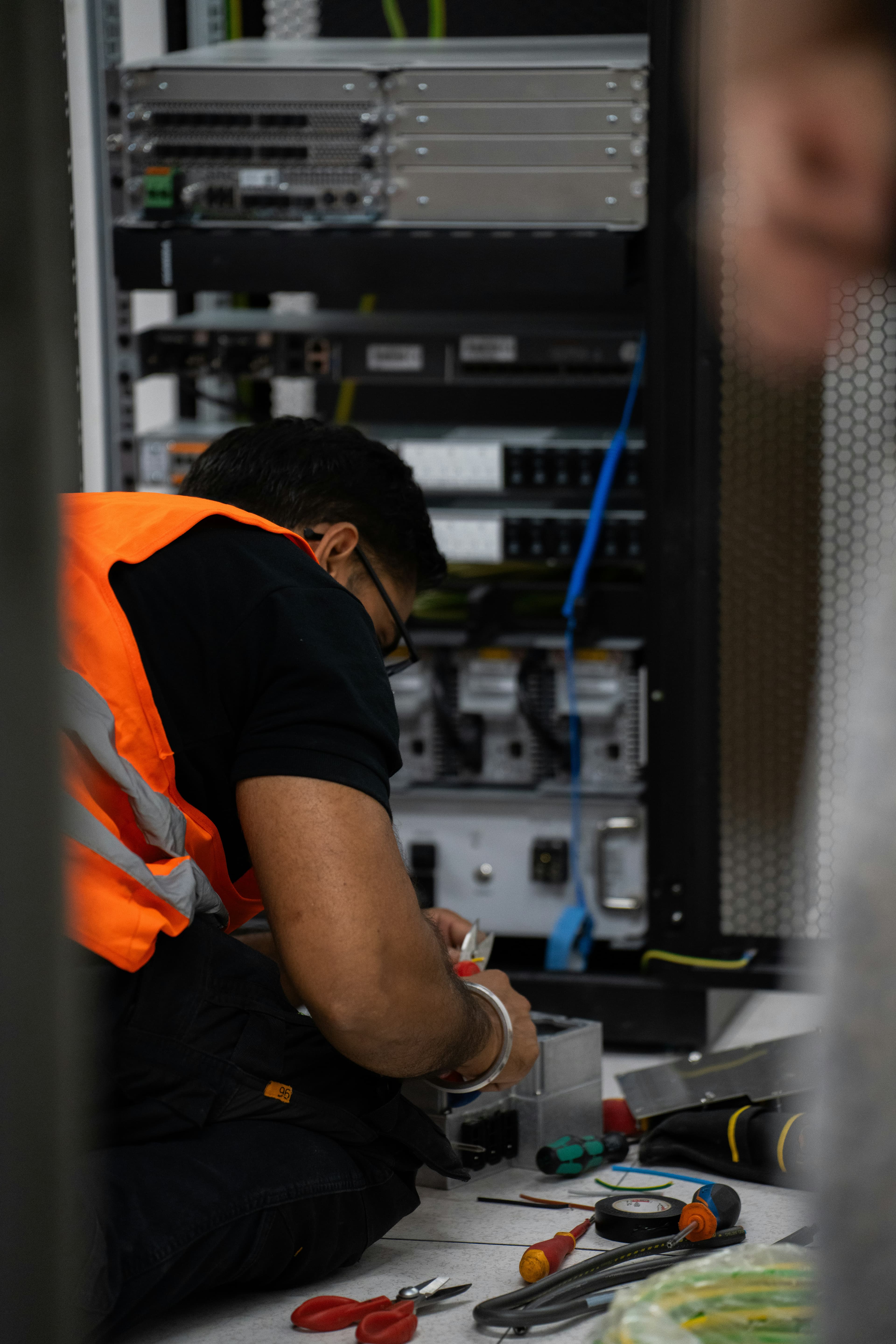 Network technician working inside an equipment cabinet during installation and testing